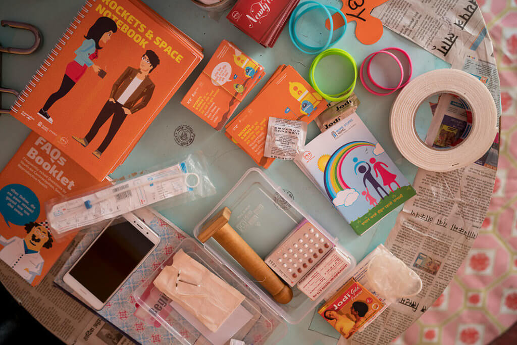 A collection of booklets about sexual health, as well as types of contraception, arranged on a table.