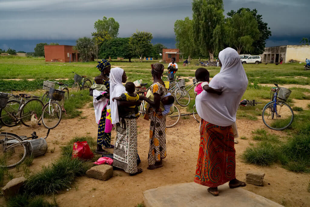 Women in head scarves holding infants outside. Many women in Burkina Faso are internally displaced and in need of reproductive healthcare.